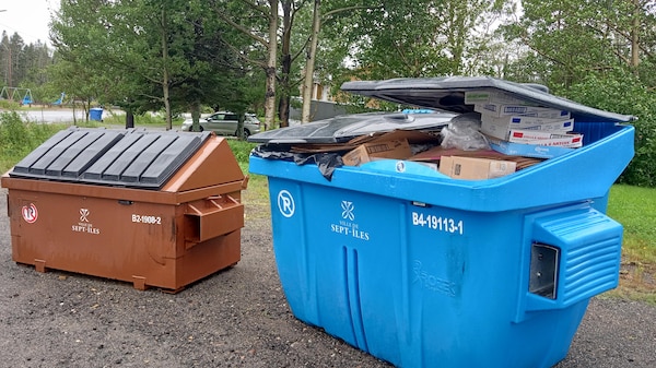 Un large conteneur de recyclage déborde de carton.