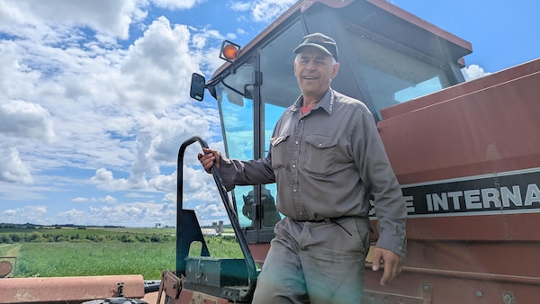 Ronald Cormier tient la poignée pour descendre de son tracteur en souriant.