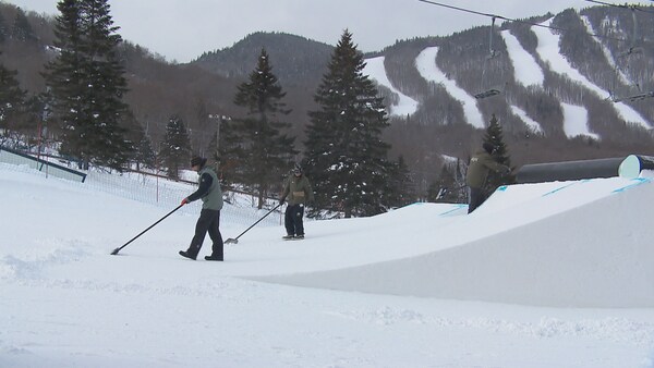 Des ouvriers préparent des sauts sur une piste de ski. 