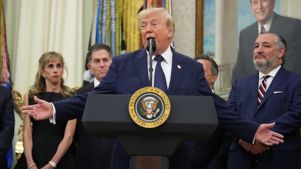Derrière un lutrin, Donald Trump parle avec des gens derrière lui.