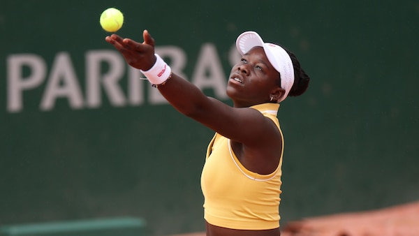 Victoria Mboko s'apprête à servir et lance la balle de tennis jaune