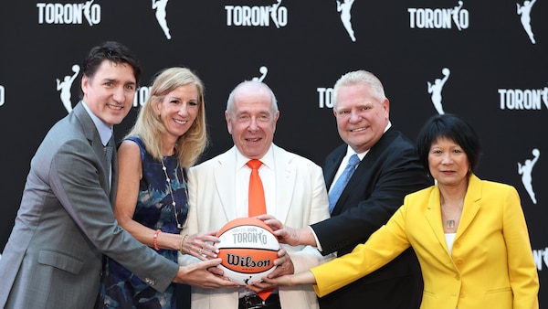 Des dignitaires tiennent ensemble un ballon de basketball.