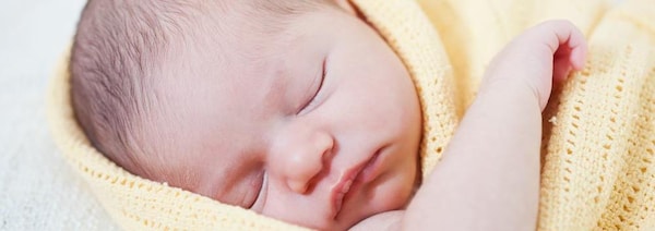Un nouveau-né dort, enveloppé dans une couverture.