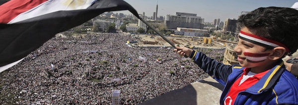  Un jeune garçons agite un drapeau, d'un balcon qui surplombe la place Tahir
