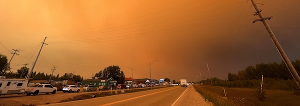 Des voitures alignées sur la route, sous un ciel orange, dimanche après-midi le 13 août 2023.
