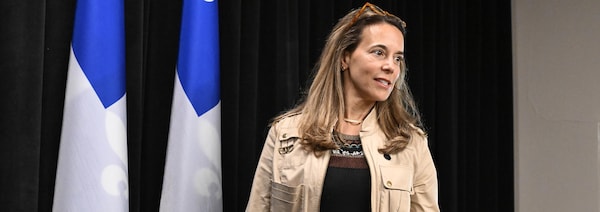 La ministre responsable de l’Habitation, France-Élaine Duranceau, debout devant deux drapeau du Québec, s'adresse aux médias.