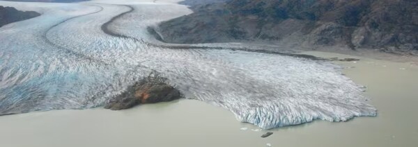 Une vue de haut d'un glacier entouré d'eau et de montagnes.