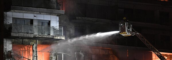 Un pompier dans une nacelle arrose un appartement en feu.