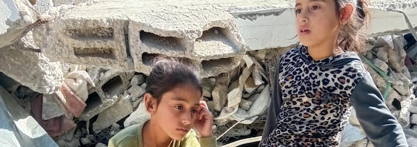 Deux jeunes filles assises sur les décombres d'une maison bombardée à Gaza.