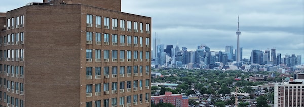 Un grand immeuble à appartement vue des airs, avec le centre-ville de Toronto à l'arrière.