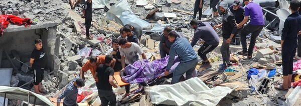 Des Palestiniens, marchant dans des débris d'une maison détruite, portent le corps d'une personne tuée.