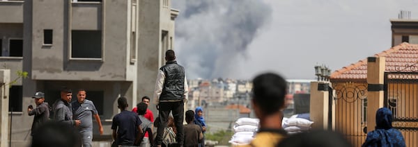 Des Palestiniens regardent une colonne de fumée noire au loin.