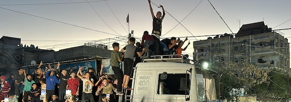 Des Palestiniens rassemblés autour et sur une camionnette lèvent les bras en l'air.
