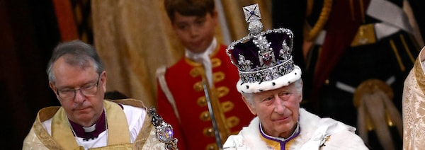 Charles III porte sa couronne et marche en tenant une baguette et une boule. 