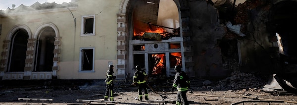 Des pompiers autour d'un édifice en flammes et gravement endommagé.