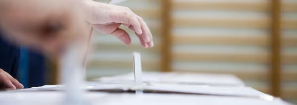 Un bulletin de vote est déposé dans une boîte de scrutin.