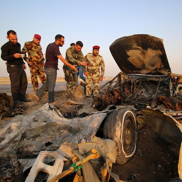 Les forces irakiennes font l'inspection d'une voiture brûlée, où a eu lieu un attentat à la bombe sur une autoroute près de la ville de Nassiriya, au sud de l'Irak.