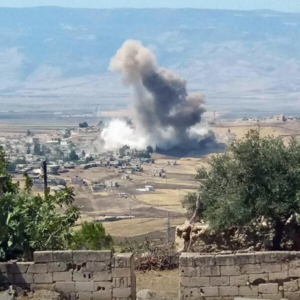 Une colonne de fumée s'élève à la suite d'une explosion dans un village syrien.