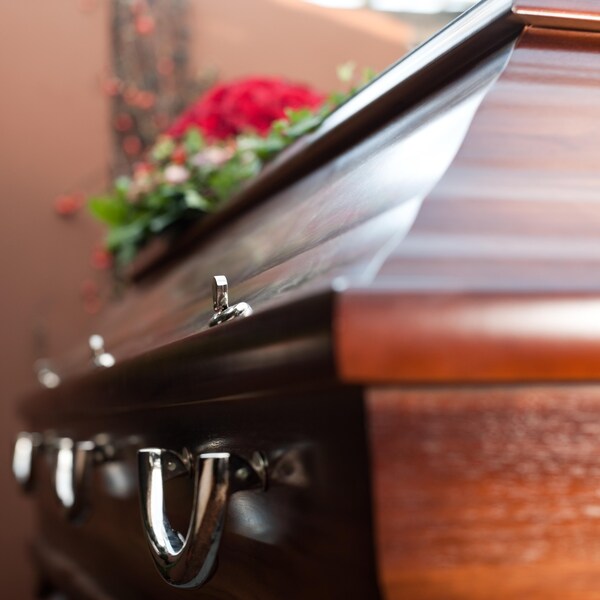 Un cercueil au cours d'une cérémonie funéraire avec des fleurs posées dessus.