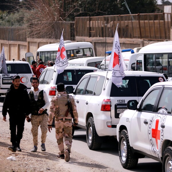Des soldats discutent près de véhicules de la Croix-Rouge internationale.