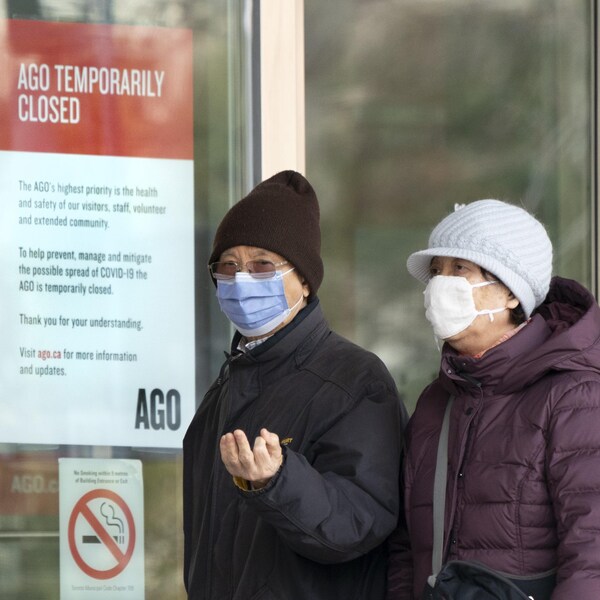 Deux aînés portant un masque passent devant un musée fermé à Toronto.