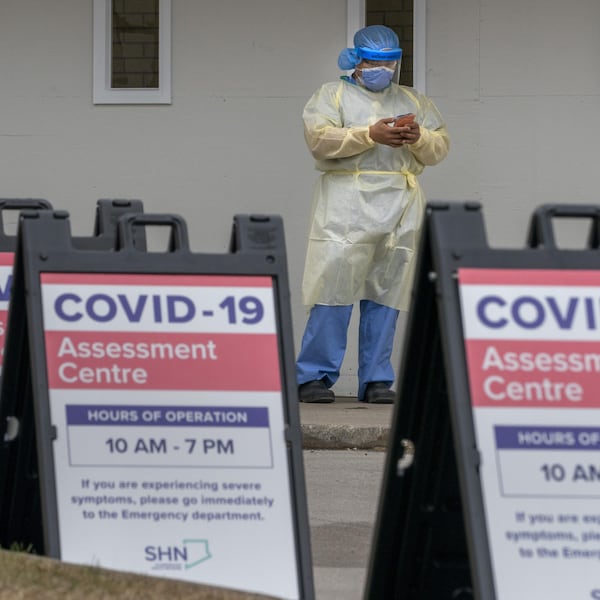 Des panneaux d'information et une infirmière à l'extérieur d'un centre de dépistage du coronavirus.