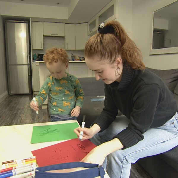 Une jeune femme dessine sur des cartons de couleur avec un enfant.