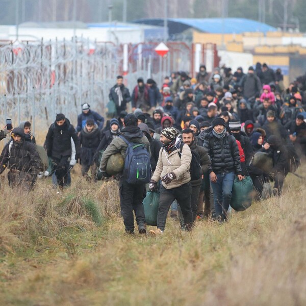 Des migrants près d'une frontière de barbelé.