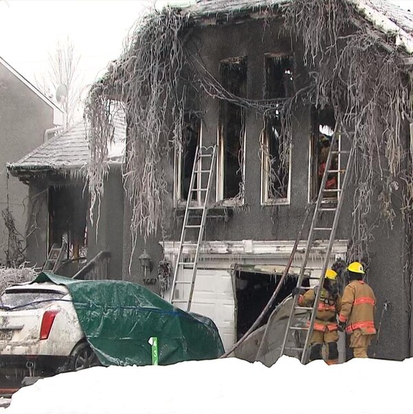 Des pompiers devant une maison calcinée.