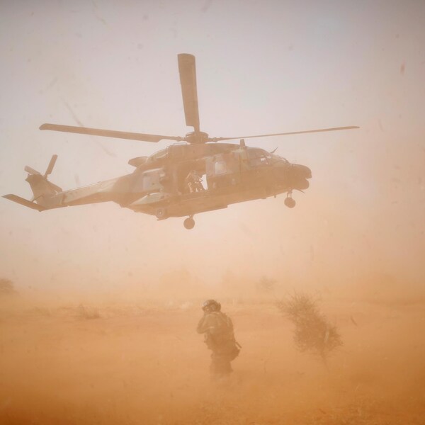 Un hélicoptère décolle au milieu d'une opération désertique. 