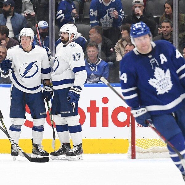 Des joueurs du Lightning célèbrent un but pendant qu'un joueur des Leafs patine dans la direction opposée.