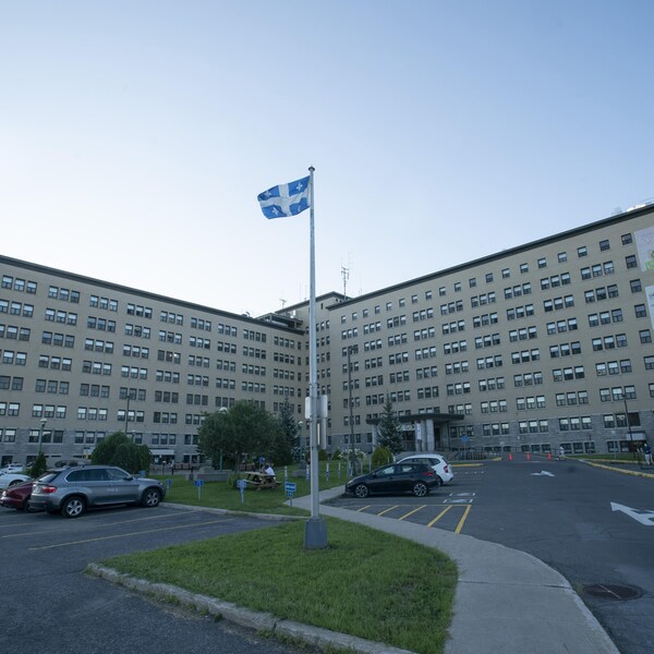 L'entrée principale de l'hôpital de Joliette, devant laquelle se trouve un stationnement. Un drapeau du Québec flotte au-dessus du stationnement.