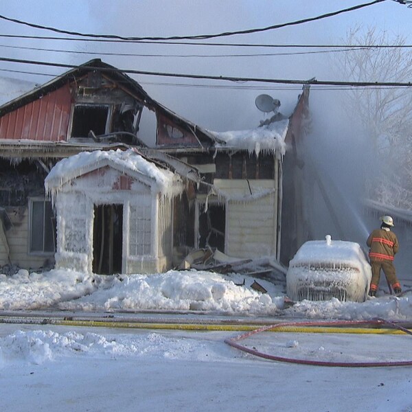 Maison glacée avec un pompier qui arrose.
