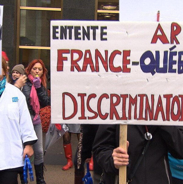 Des infirmières tiennent des pancartes sur lesquelles on peut lire : « entente France-Québec discriminatoire » et « infirmier(e) français(e) non-reconnaissance 2 vitesses ».