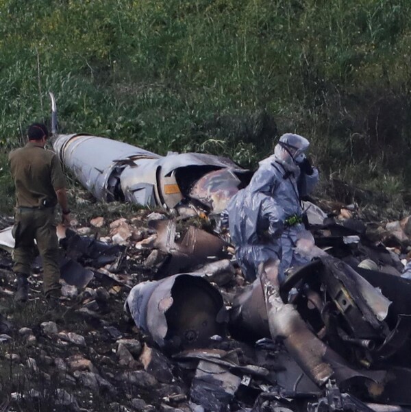 Des membres des forces de sécurité israéliennes examinent les restes de l'appareil de type F-16 qui s'est écrasé. 