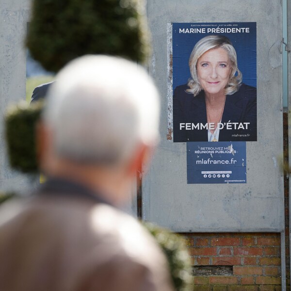 Une homme regarde les affiches des deux politiciens. 