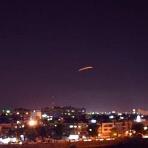 Damas est éclairée par les lumières de la ville. En pleine nuit, un tir de missile est visible dans le ciel, au loin.