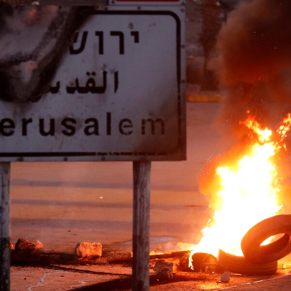 Un manifestant jette un pneu dans une barricade en feu, près de la ville de Ramallah, en Cisjordanie.