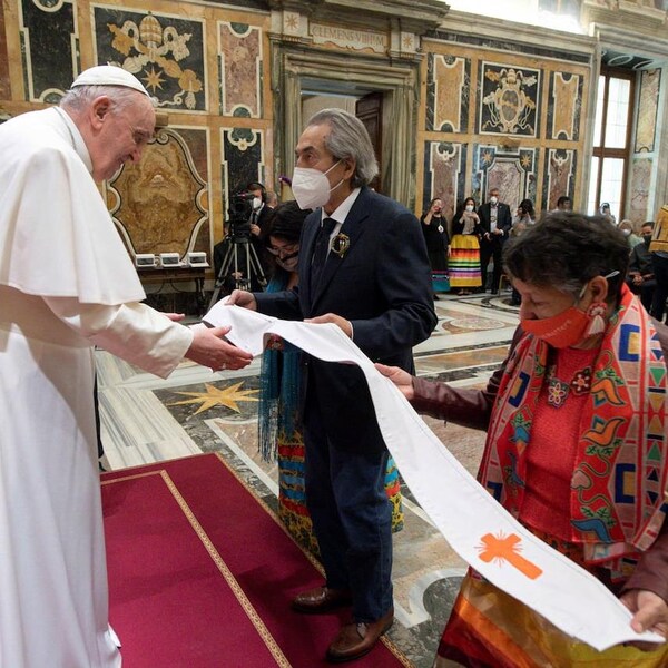 Le pape François se penche pour observer l'étole blanche que tendent quelques représentants autochtones, dont Phil Fontaine.