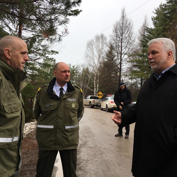 Philippe Couillard discute avec deux agents de la Sûreté du Québec.