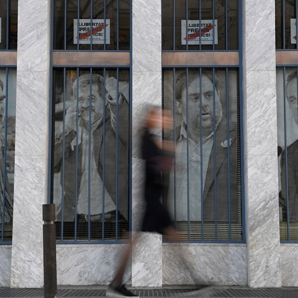 Une femme passe devant des affiches sur lesquelles on voit des photos des dirigeants catalans Jordi Cuixart, Jordi Sanchez, Oriol Junqueras et Joaquim Forn.