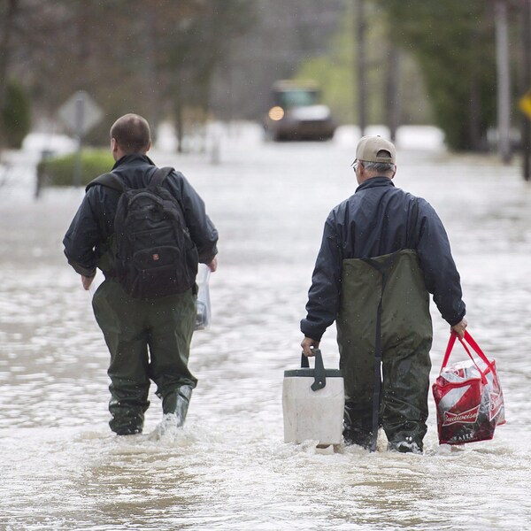 Deux hommes transportent certaines de leurs possessions dans une rue inondée de Rigaud.