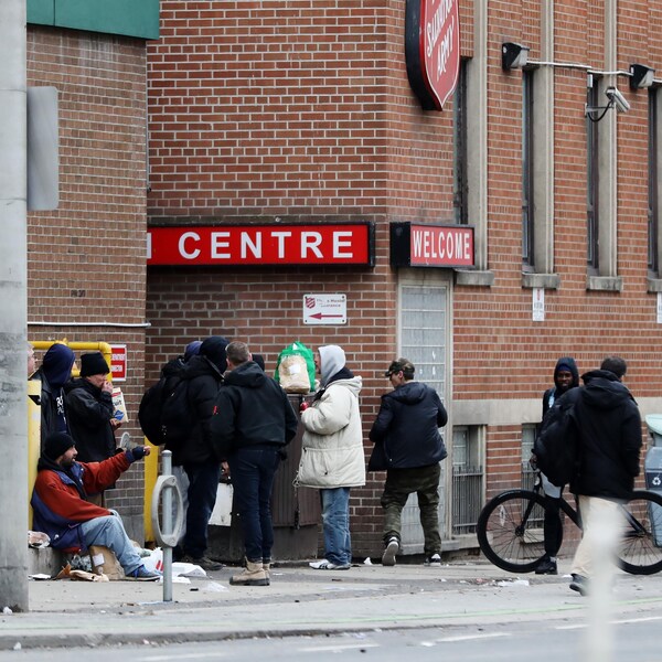 Des hommes attendent à l'entrée d'un refuge à Toronto.