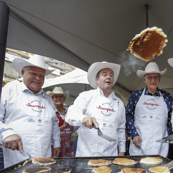 Cinq hommes qui portent des chapeaux de cowboy font cuire des crêpes.