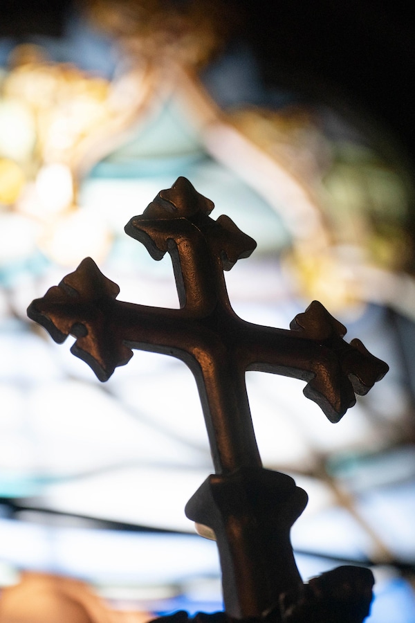 Photo d'une croix avec un vitrail en arrière-fond.