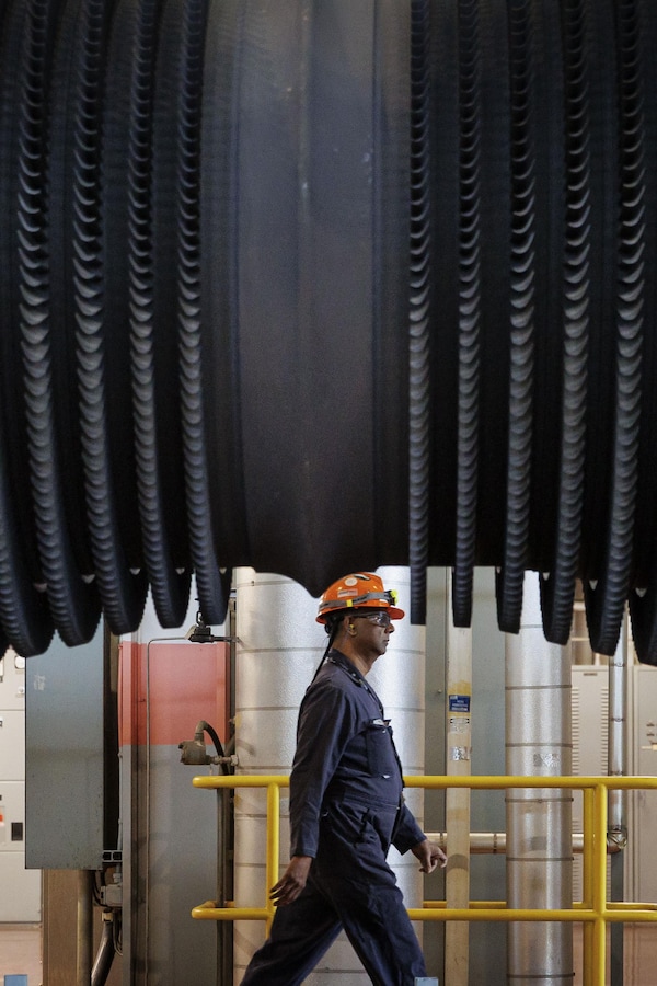 Un travailleur d'Ontario Power Generation en uniforme passe devant un ventilateur de turbine en cours d'entretien à la centrale nucléaire de Pickering. 