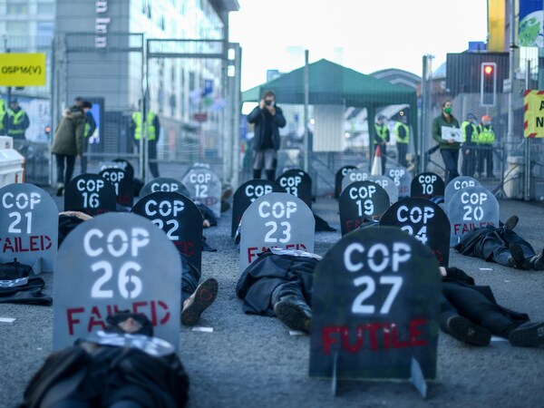Des gens couchés par terre avec des panneaux qui dénoncent les conférences sur le climat comme des échecs. 