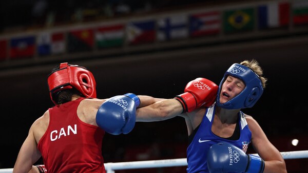 Une boxeuse en rouge frappe durement son adversaire, en bleu, de la droite pendant un combat.