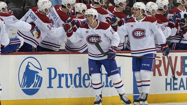 Des joueurs en blanc sont félicités par leurs coéquipiers à leur banc.