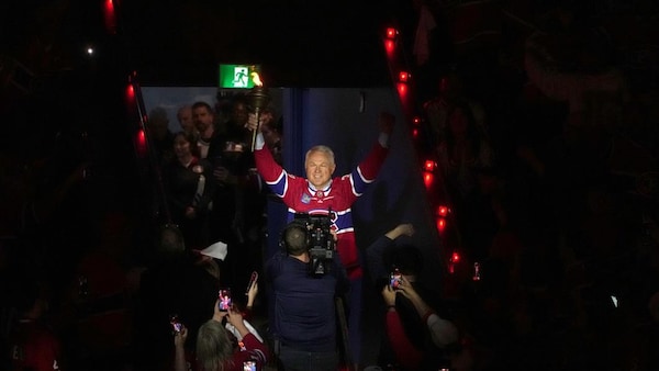 Un homme tient le flambeau et salue la foule en entrant dans le Centre Bell.